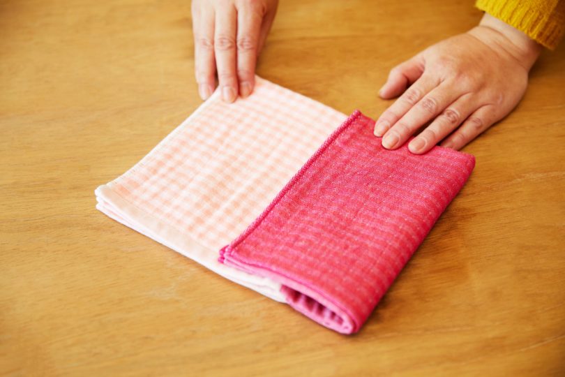 フェイスタオルの長辺を三つ折りにし、この状態から、さらに長辺を三つ折りにする。