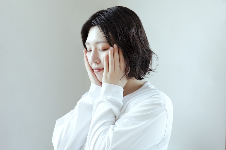 女性が手で顔を優しく包み込む様子