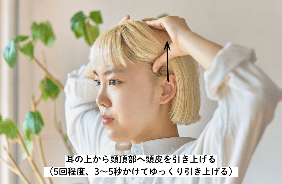 耳の上から頭頂部へ頭皮を引き上げる